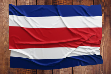 Flag of Costa Rica on a wooden table background. Wrinkled Costa Rican flag top view.