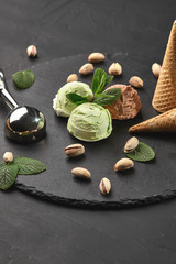 Gourmet chocolate and pistachio ice cream served on a stone slate over a black background.