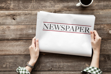 Woman reading newspaper on wooden background