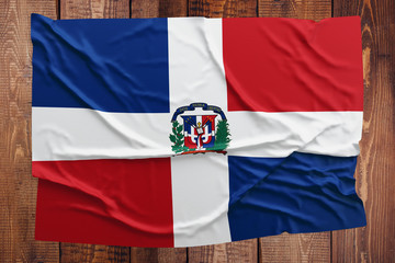 Flag of Dominican Republic on a wooden table background. Wrinkled Dominican flag top view.