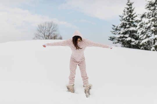 Beautiful woman playing in the snow wearing onesie