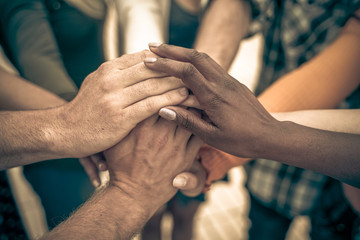 Young people putting their hands together. Friends with stack of hands showing unity and teamwork – Image - obrazy, fototapety, plakaty