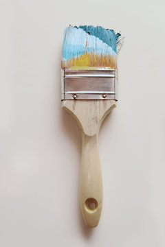 Paintbrush in blue paint on plain background