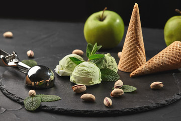 Gourmet pistachio ice cream served on a stone slate over a black background.