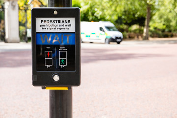 Traffic light for pedastrians in UK (Britain) for safe road crossing; blured police car in the background