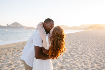 Affectionate, kissing just-married couple together at sunset on