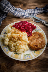 Pork cutlet with minced meat served with boiled potatoes and beetroot.