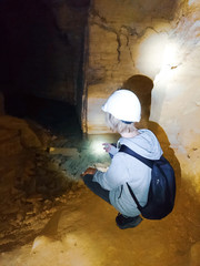 boy teenager in a construction helmet walks through the catacombs