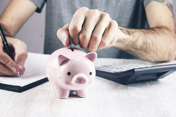 Man putting coin in piggy bank.