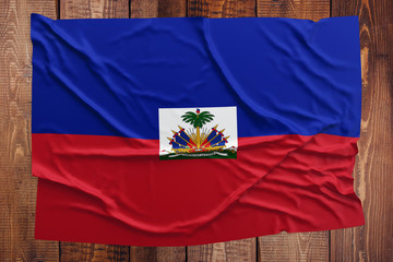 Flag of Haiti on a wooden table background. Wrinkled Haitian flag top view.