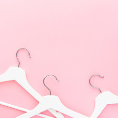 White hangers on pastel pink background