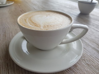 Cup of coffee with cream on wooden background