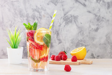 Lemonade with berries and mint. Next to the cutting board are the ingredients. Summer refreshing drink in a tall glass. Light picture with copy space.