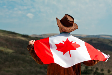 A man in a cowboy hat take canadian flag