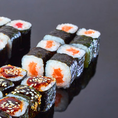 Various kinds of tasty sushi roll on black background for menu. Japanese food