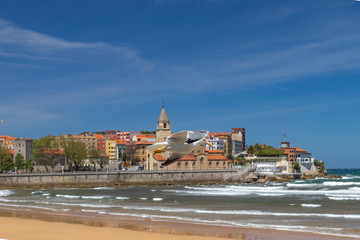 Beautiful seagull flies in stormy weather against the backdrop of an ancient city and a sandy beach with ocean surf