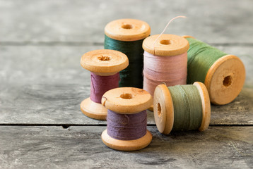 Fototapeta na wymiar Sewing kit. Spools of colored thread on old wooden table.