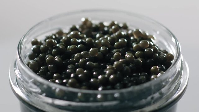 Black Caviar rotated background Seafood High quality natural sturgeon black caviar close-up, rotation Glass jar Expensive