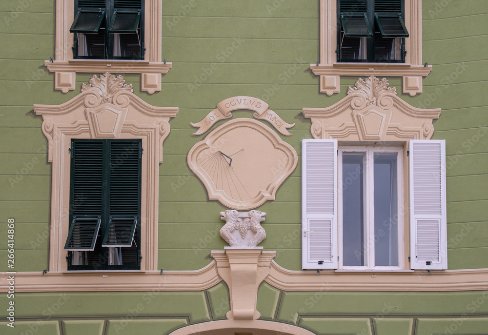 Wall mural close-up of the facade of an old building with bas-reliefs and a sundial with the motto 