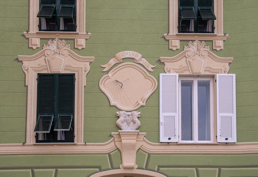 Close-up of the facade of an old building with bas-reliefs and a sundial with the motto "Sol oculus mundi" ("The sun is the eye of the world") painted on a green wall, Sestri Levante, Liguria, Italy