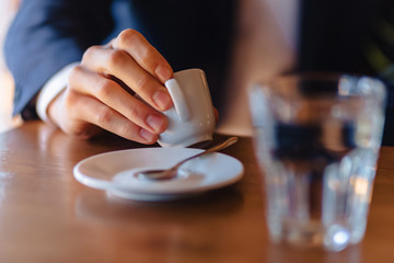 Fototapeta na wymiar espresso coffee cup in stylish men's hand, morning coffee at cafe