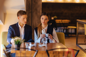 A stylish couple drinks morning coffee at the cafe, young businessmen and freelancers