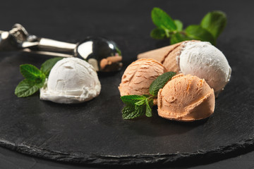 Close-up shot of a creamy and orange ice cream served on a dark slate, black background.