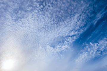 Light small cirrocumulus clouds on a bright sunny blue sky. Heavenly daylight background. - obrazy, fototapety, plakaty