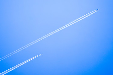 Two planes flying high in the sky, leaving white streaks