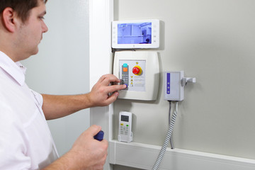 Doctor dentist connects x-ray equipment and oversees the passage of the procedure in the preliminary room. The concept of health and modern medicine.