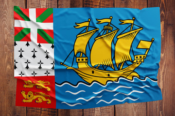 Flag of Saint Pierre And Miquelon on a wooden table background. Wrinkled flag top view.