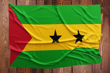 Flag of Sao Tome And Principe on a wooden table background. Wrinkled flag top view.