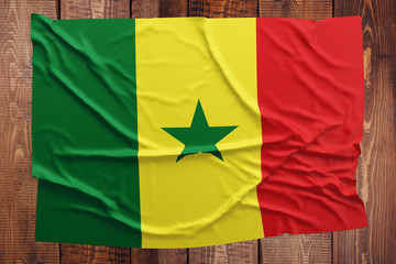 Flag of Senegal on a wooden table background. Wrinkled Senegalese flag top view.