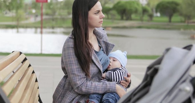 Mom breastfeeds a child in the park