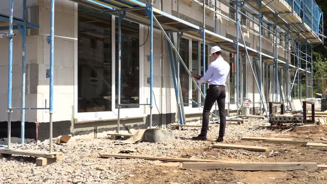 Architect inspects construction outside talking on the phone