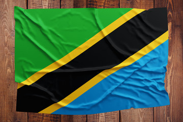 Flag of Tanzania on a wooden table background. Wrinkled Tanzanian flag top view.