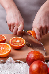 young woman in a gray apron cuts blood orange