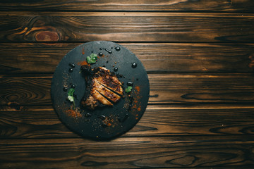 Pork bone steak on a wooden background with honey. Board slate. kenza, pepper