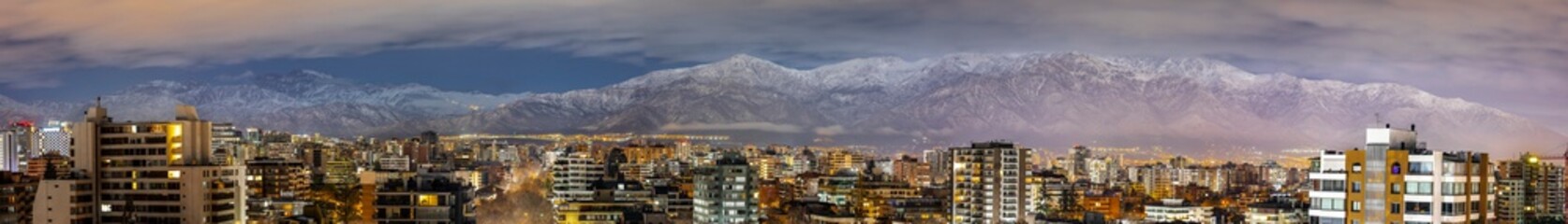 Amazing views of Santiago de Chile skyline by night with the Andes mountain range full of snow and...
