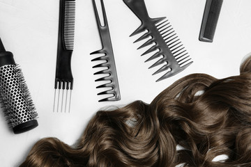 Flat lay composition with brown hair and hairdresser's tools on light background