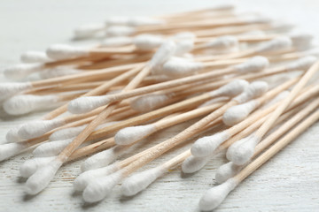 Pile of cotton swabs on white wooden background, closeup