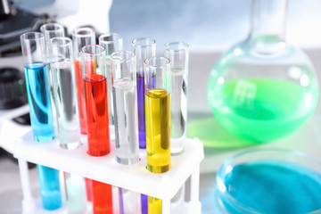Test tubes with samples in rack on table at chemistry laboratory, closeup