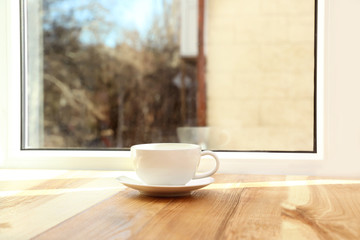 Cup of hot winter drink on wooden windowsill, space for text