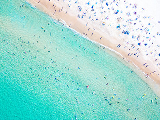 Obraz premium Widok z lotu ptaka na plażę Bondi w idealny letni dzień z ludźmi pływającymi i opalającymi się. Bondi to jedna z najbardziej ruchliwych plaż w Sydney i znajduje się na wschodnim wybrzeżu Australii