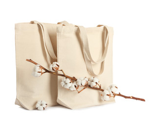 Stylish eco bags and cotton flowers on white background