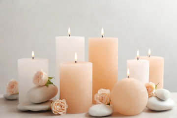 Fototapeta na wymiar Beautiful composition with candles on table against grey background