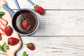 Chocolate fondue with strawberries and marshmallow on wooden table
