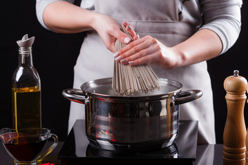 young woman in a gray aprons is preparing a noodle soba