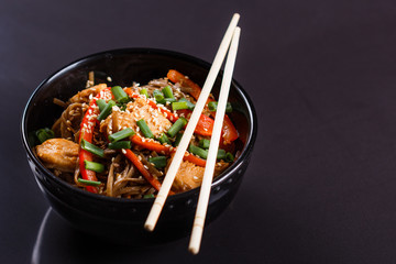 Buckwheat noodle in a black bowl on chicken fillet