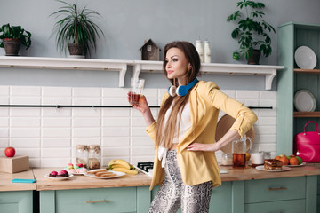 Side view of beautiful girl preparing for job in morning and drinking juice at home. Young woman in...
